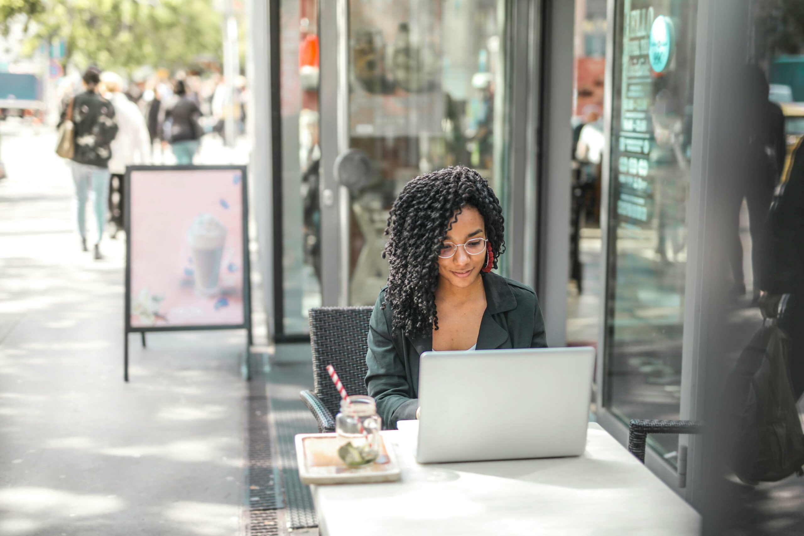 Ethnische Junge Frau, Die Laptop Verwendet, Während Sie Leckeres Getränk Im Modernen Straßencafé Hat